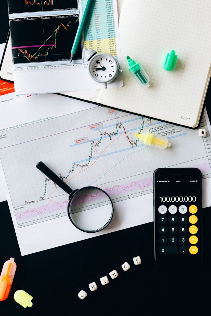 Stock market analysis setup with graphs, calculator, and magnifying glass.